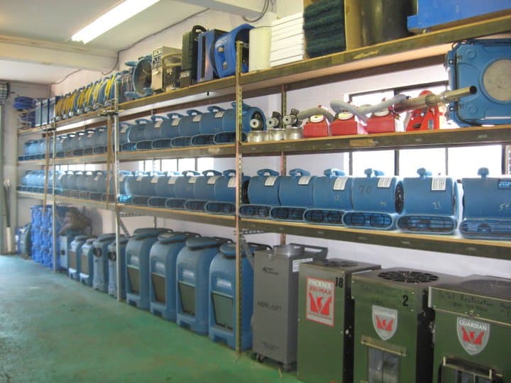 Rows of air movers and dehumidifiers stored on warehouse shelving